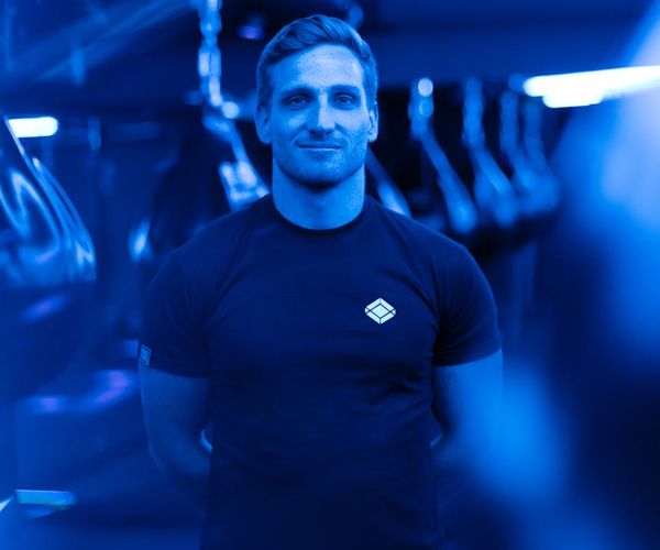 Person stretching in a modern gym with neon blue lighting.